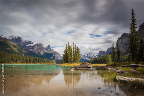 Long exposure landscape of Rocky mountains reflected on clear and green lake water with spruce and pine trees under a cloudy sky  Spirit Island  Maligne Lake  Jasper National Park  Alberta  Canada