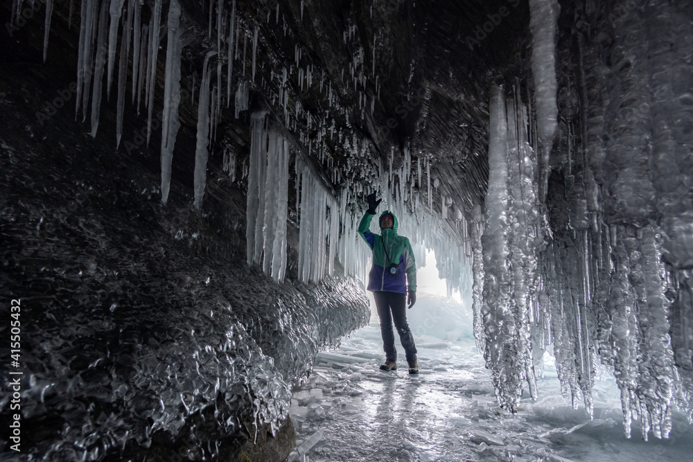 Fototapeta premium A tourist admires icicles in an ice grotto on Lake Baikal