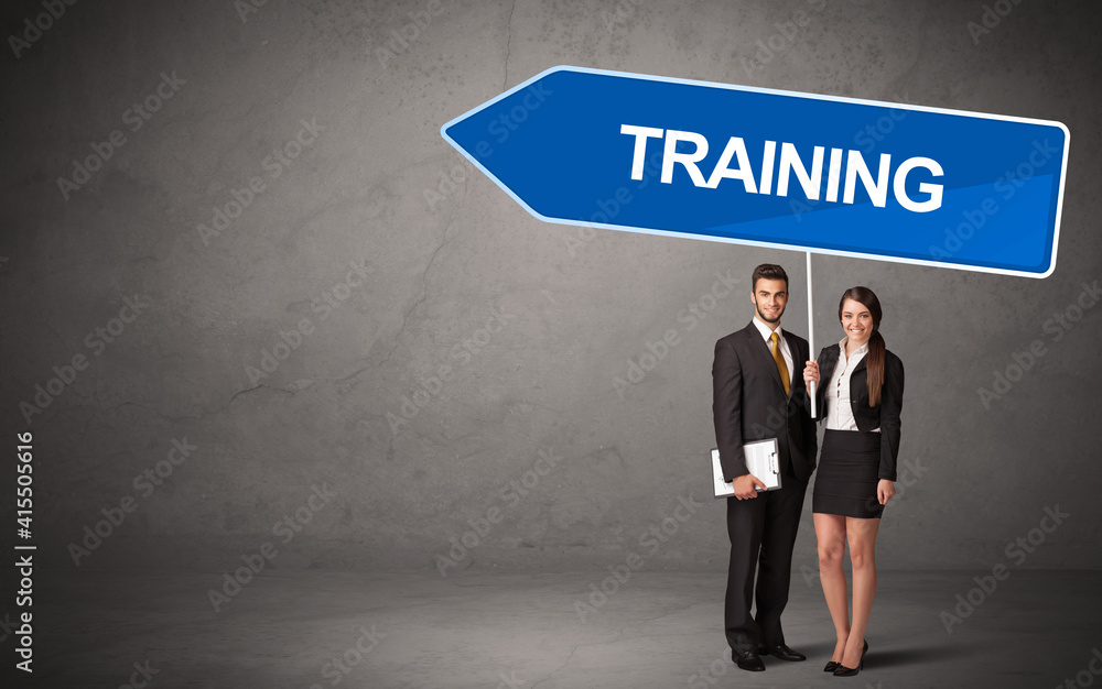 Fototapeta premium Young business person in casual holding road sign with TRAINING inscription, new business direction concept