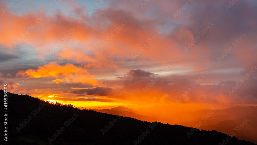 High viewpoint of an intense orange sunset with clouds and rain in the cloud forest, Dota, Costa Rica highlands