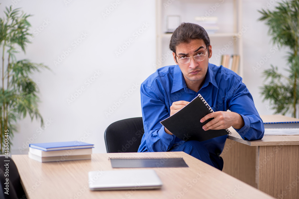 Young male teacher checking notes in the classroom Young male teacher checking notes in the classroom