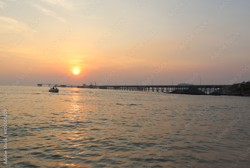cement bridge in the sea for boats to dock and have the sunset in the evening. There is the shadow of the sun in the calm sea It gives a feeling of comfort and relaxation on vacation. in Thailand.