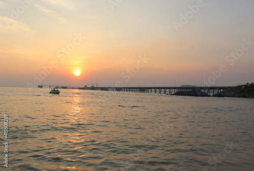 cement bridge in the sea for boats to dock and have the sunset in the evening. There is the shadow of the sun in the calm sea It gives a feeling of comfort and relaxation on vacation. in Thailand.