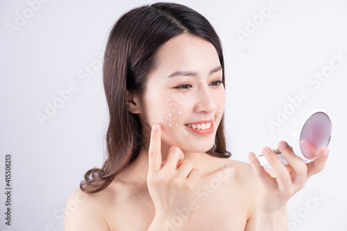 Young Asian girl with a happy expression sitting with cream on the background