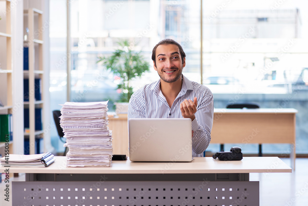Young male employee unhappy with excessive work in the office Young male employee unhappy with excessive work in the office