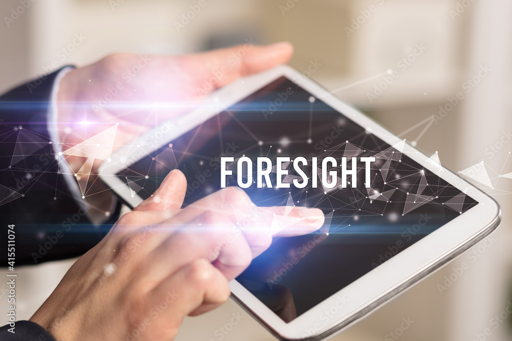 Close up hands using tablet with FORESIGHT inscription, modern business technology concept Close up hands using tablet with FORESIGHT inscription, modern business technology concept