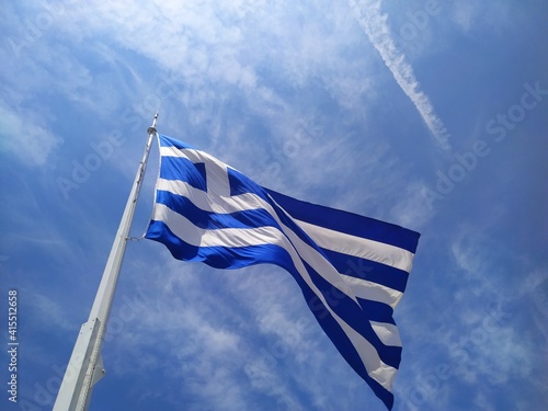 Bandera griega flameante en un cielo azulado