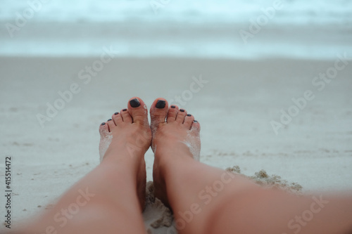 Woman's feet on sand, relaxaion, traveling,  skin care, beauty pedicure, nail polish concept. Closeup  photo