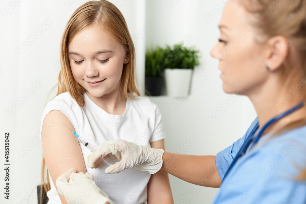 Obraz premium woman doctor giving a girl an injection in the arm vaccination
