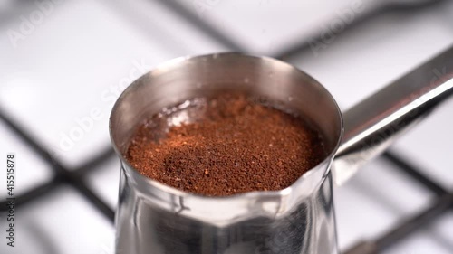 Pouring coffee ground into turkish coffee pot. Slow motion.