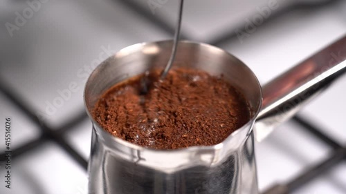 Mixing coffee with teaspoon while preparation in turkish coffee pot