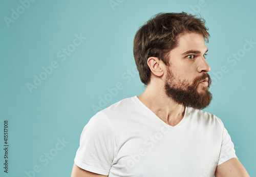 Guy in a white t-shirt brunet on a blue background cropped view puzzled look side view