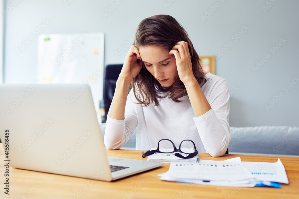 Stressed young woman sitting at desk working from home office Stressed young woman sitting at desk working from home office