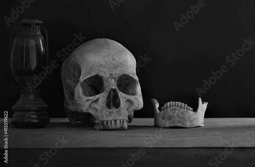 Awesome, Skull and Jaw with old lantern on the plank and dark background .
