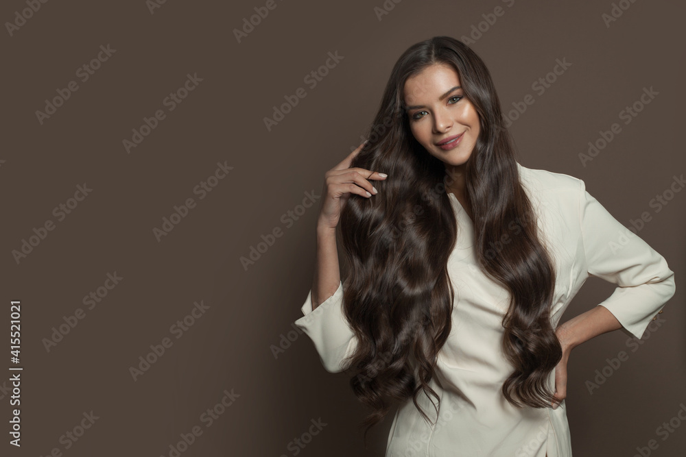 Smiling woman with healthy curly hairstyle wearing white dress standing on brown background Smiling woman with healthy curly hairstyle wearing white dress standing on brown background
