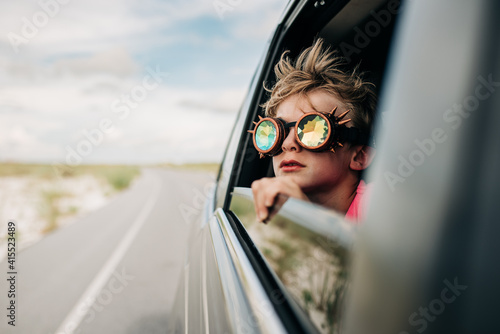 Quadro su tela Child in kaleidoscope goggles looks out the car window while on a road trip for