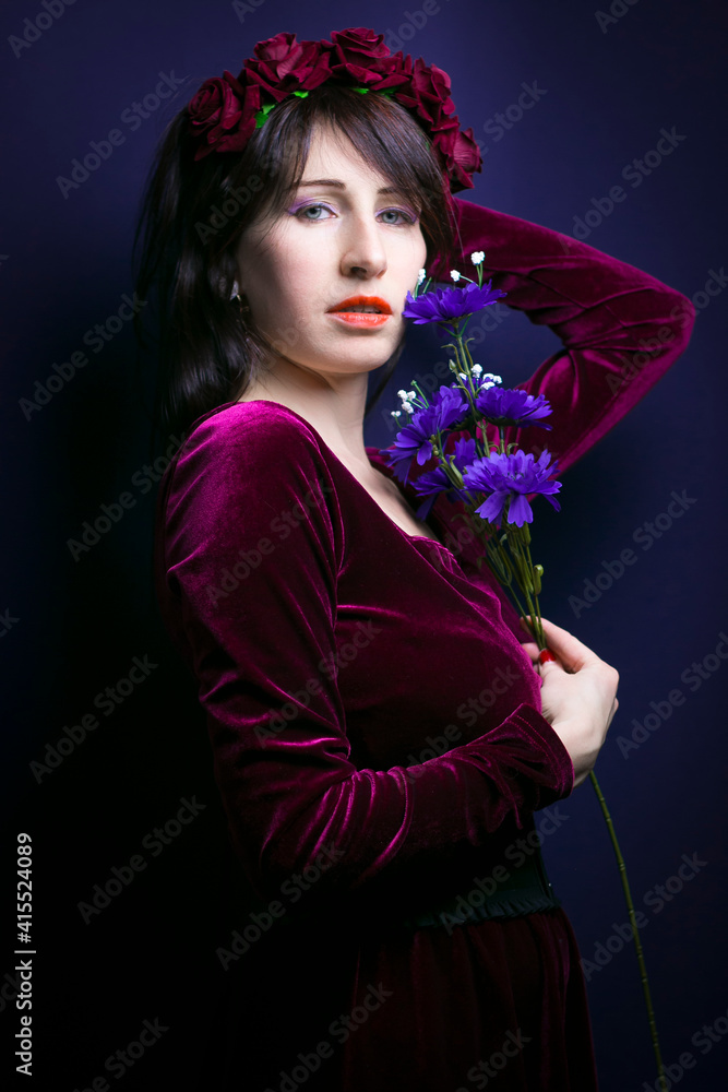 Naklejka premium Spring portrait of beautiful fashion model with flowers isolated on blue background