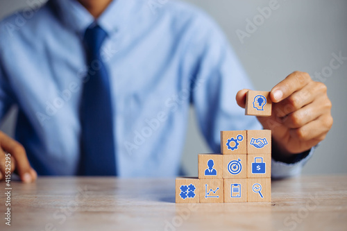 Businessman hand arranging wood block with icon business strategy and Action plan