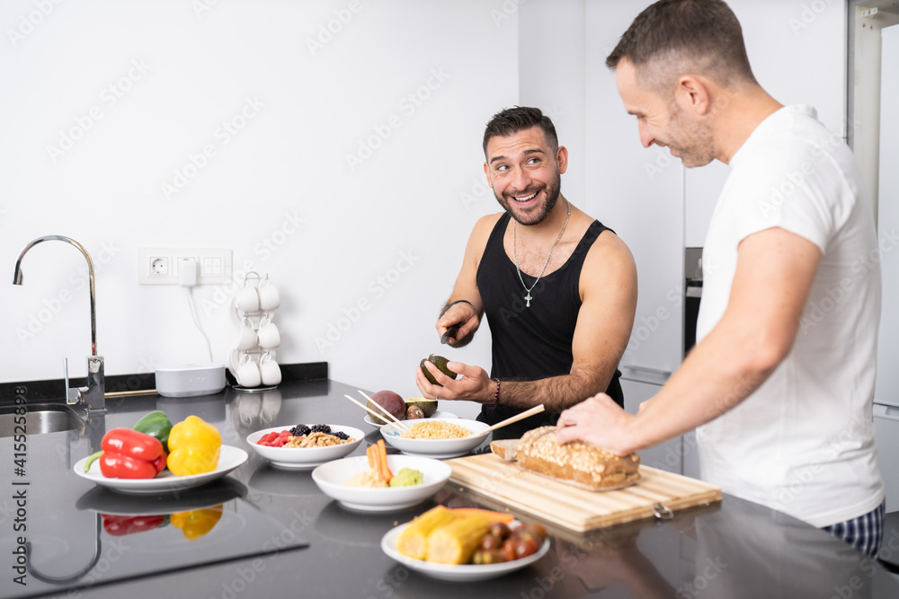 Gay couple cooking healthy vegan food together at home.