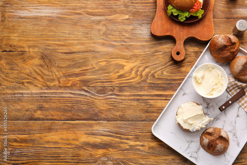 Bun and bowl with tasty cream cheese on wooden background Bun and bowl with tasty cream cheese on wooden background