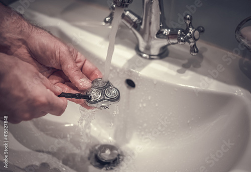 Photography Cleaning razor blades under running water in the bathroom, men's hands with a sm