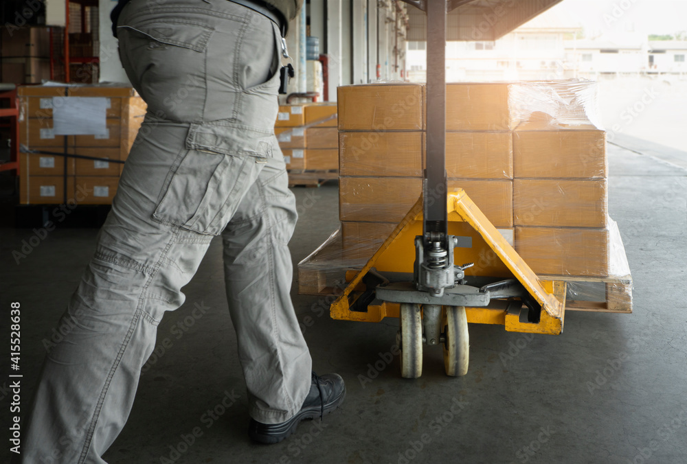 Worker working with hand pallet jack unloading cargo boxes at storage warehouse. shipment boxes. Worker working with hand pallet jack unloading cargo boxes at storage warehouse. shipment boxes.