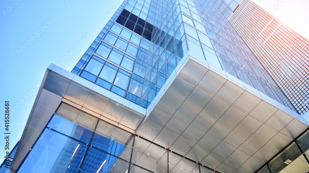 Obraz premium Downtown corporate business district architecture. Glass reflective office buildings against blue sky and sun light. Economy, finances, business activity concept. Rising sun on the horizon.