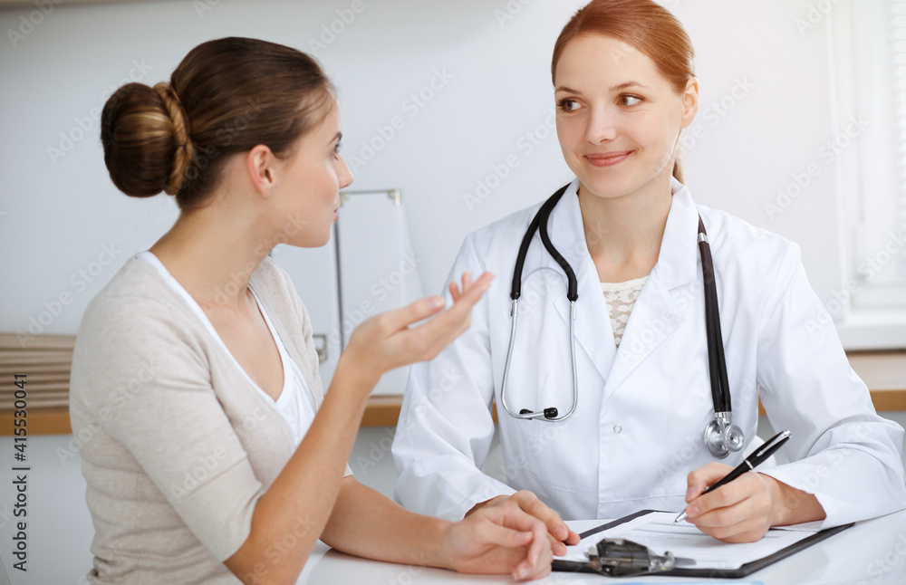 Doctor and patient sitting and discussing health examination results in sunny clinic office Doctor and patient sitting and discussing health examination results in sunny clinic office