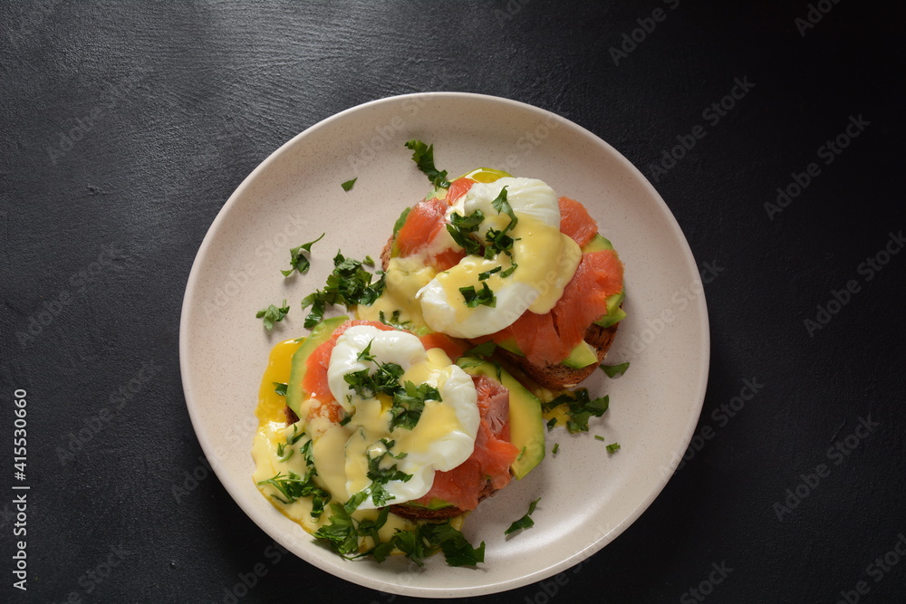 Eggs Benedict with smoked salmon, avocado slices and hollandaise sauce Eggs Benedict with smoked salmon, avocado slices and hollandaise sauce