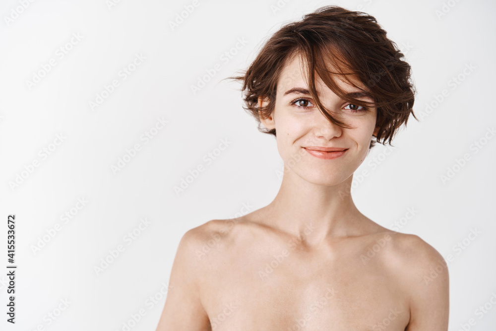 Beauty. Young caucasian woman with naked body and no makeup facial skin, hydrated and clean face after cleansing gels and face cream, standing over white background Beauty. Young caucasian woman with naked body and no makeup facial skin, hydrated and clean face after cleansing gels and face cream, standing over white background