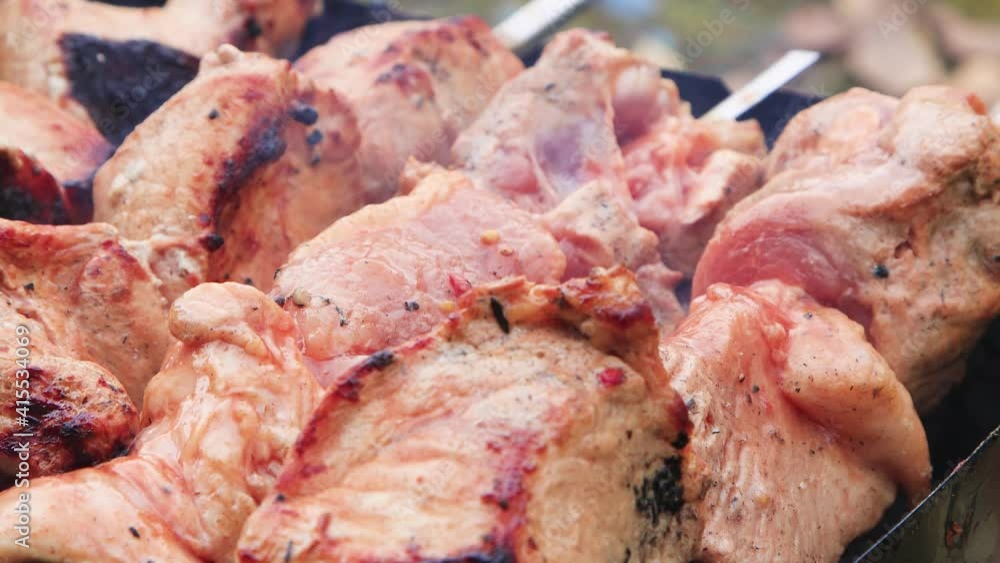 Large cuts of meat are grilled and fanned. Shish kebab preparation stage. Making food on fire. Outdoor picnic in nature. Warm day, soft sunshine. Close-up. UHD. Large cuts of meat are grilled and fanned. Shish kebab preparation stage. Making food on fire. Outdoor picnic in nature. Warm day, soft sunshine. Close-up. UHD.