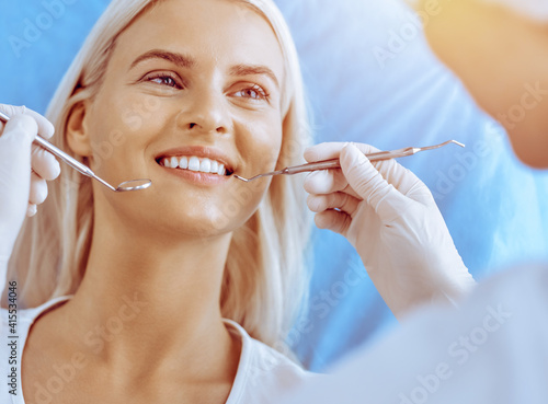 Smiling blonde woman examined by dentist at dental clinic. Healthy teeth in medicine concept
