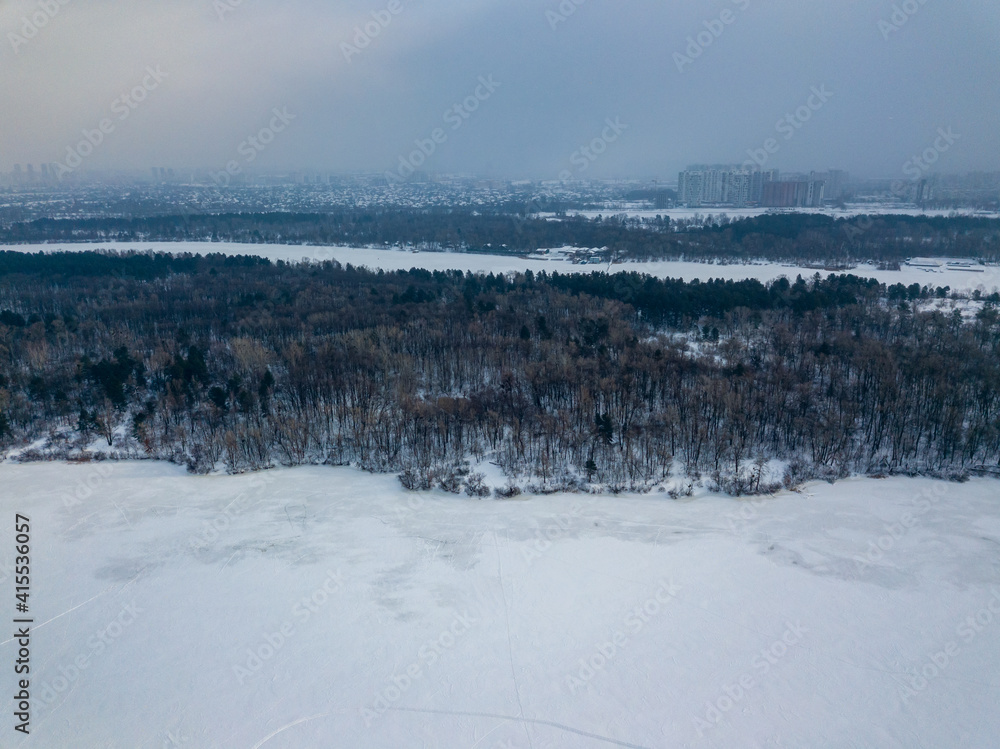 The frozen Dnieper river in Kiev. Aerial drone view. Winter frosty morning. The sun breaks through the clouds.