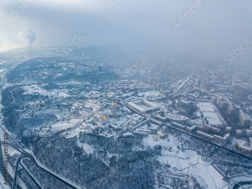 Snow-covered Kiev-Pechersk Lavra in a blizzard. Aerial drone view. Snowy winter morning, blizzard. Black cloud over the city.