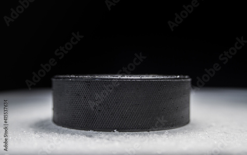 Hockey puck on the ice rink, with copy space on black background.
