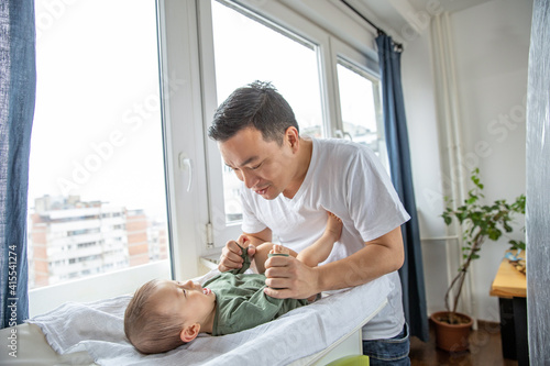 Father changing diapers to his newborn son