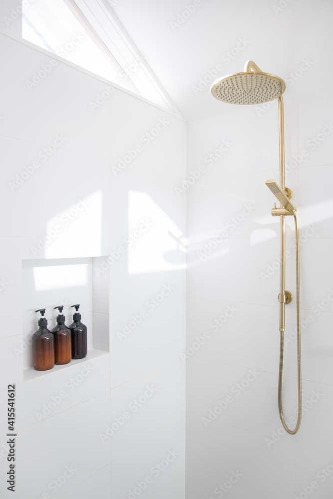 Modern bathroom white tiled shower gold brass tap bottles shampoo conditioner wash small space slanted roof tiled wall elegant natural light renovation new Modern bathroom white tiled shower gold brass tap bottles shampoo conditioner wash small space slanted roof tiled wall elegant natural light renovation new