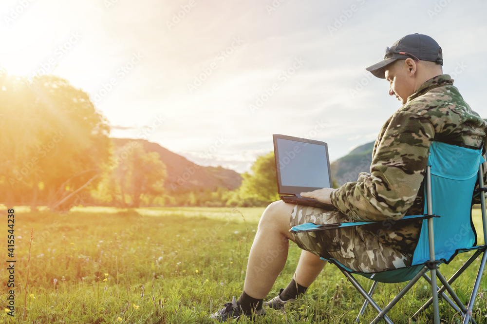men using laptop outdoors at sunset men using laptop outdoors at sunset