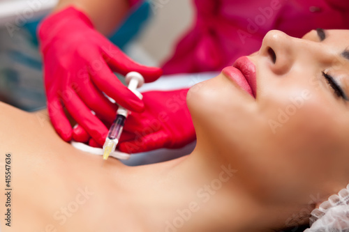 Woman lying on bed while getting beauty injection in neck. Facial treatments. Beauty concept.