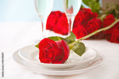 Romantic restaurant table setting for two with roses on the plate