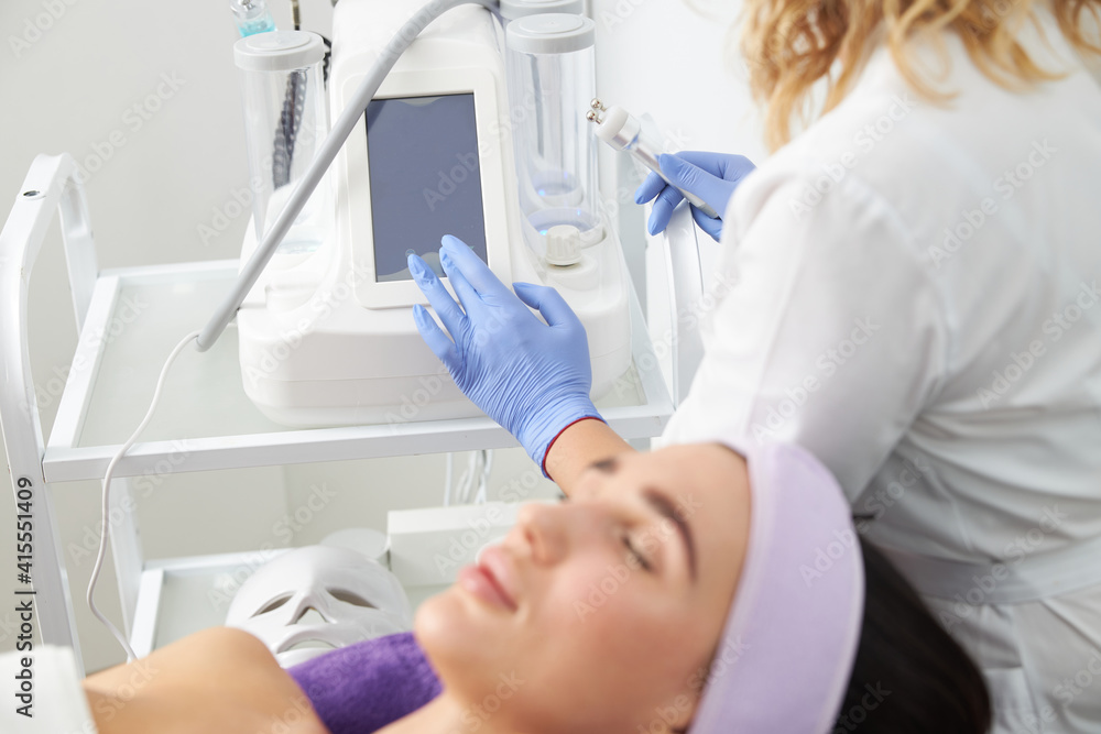 Professional cosmetologist is doing procedures for client in light cabinet Professional cosmetologist is doing procedures for client in light cabinet