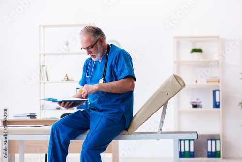 Old male doctor taking notes in the clinic