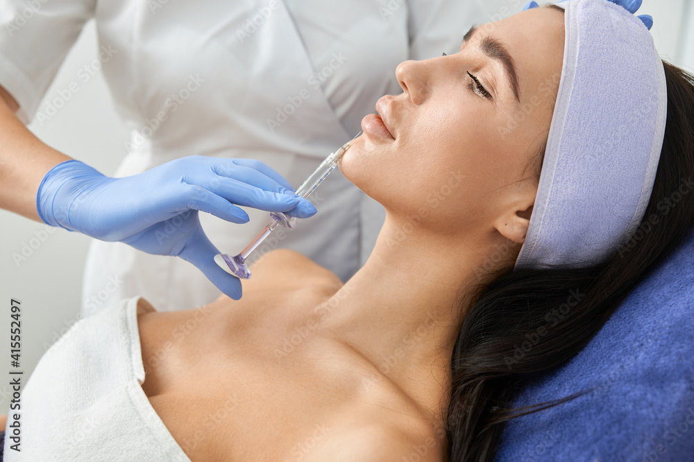 Professional cosmetologist is doing procedures for client in light cabinet Professional cosmetologist is doing procedures for client in light cabinet