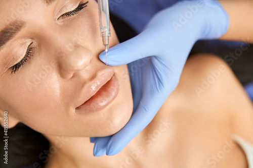 Professional cosmetologist is doing procedures for client in light cabinet