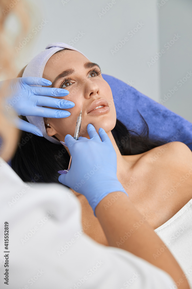 Professional cosmetologist is doing procedures for client in light cabinet Professional cosmetologist is doing procedures for client in light cabinet
