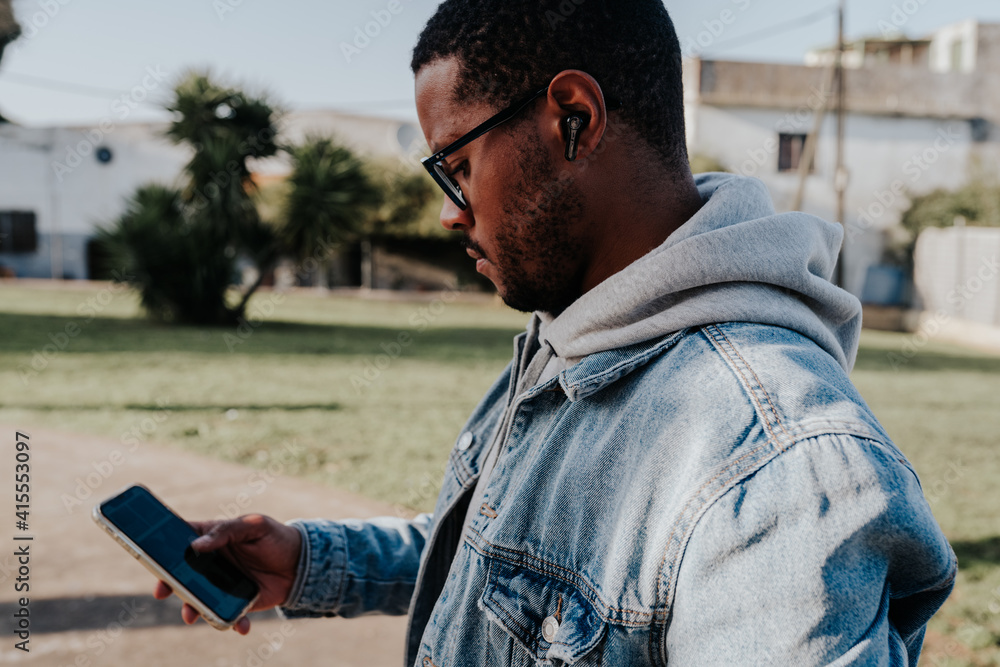 Obraz premium black boy in park listening to music with headphones