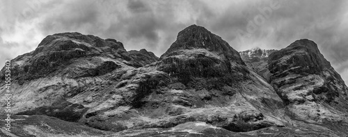 Majestic moody  black and white landscape image of Three Sisters in Glencoe in Scottish Highlands on a wet Winter day wit high water running down mountains photo