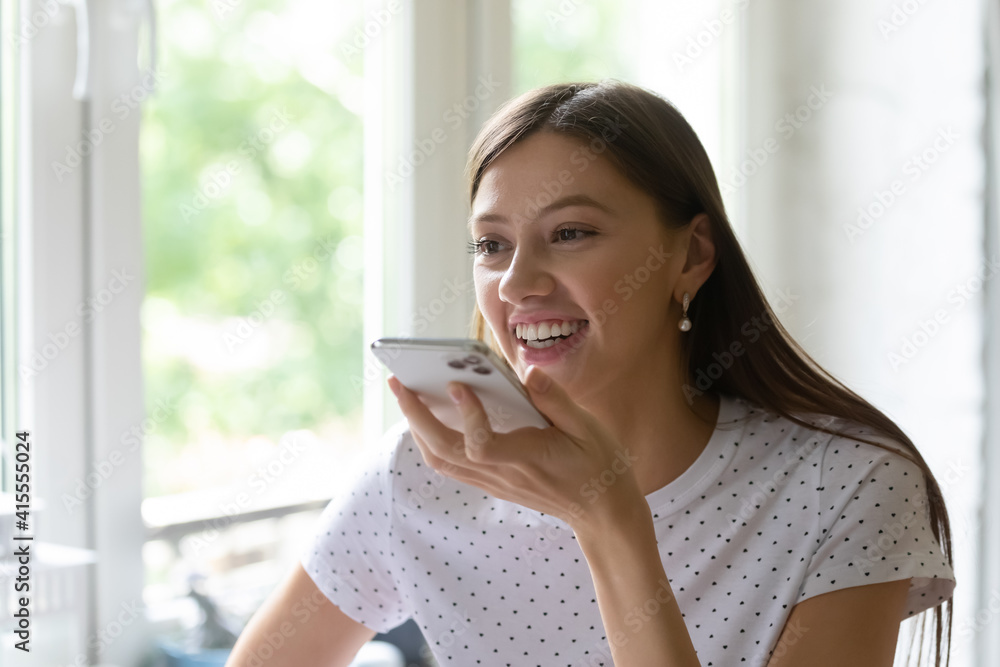 Close up of happy young Caucasian woman record audio message on modern smartphone, talk on loudspeaker on gadget. Smiling millennial female activate digital voice assistant app on cellphone. Close up of happy young Caucasian woman record audio message on modern smartphone, talk on loudspeaker on gadget. Smiling millennial female activate digital voice assistant app on cellphone.