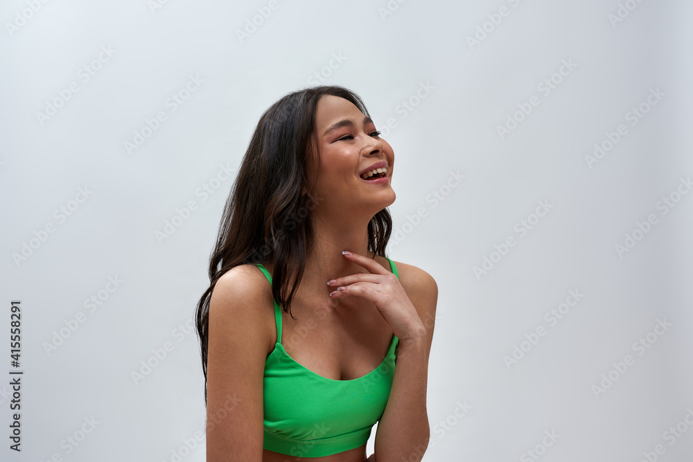 Cheerful young woman wearing green underwear looking happy, laughing aside while posing isolated over light background Cheerful young woman wearing green underwear looking happy, laughing aside while posing isolated over light background
