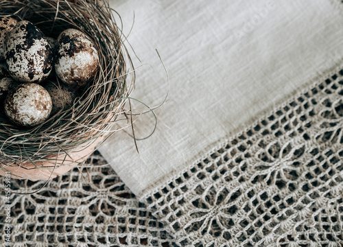 Small quail eggs in Easter nest on a natural linen background. Zero Waste Easter pattern. Flat lay, close-up, copy space.